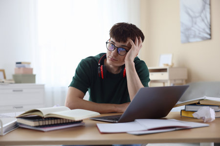 Tired student preparing for exam at table indoorsの写真素材