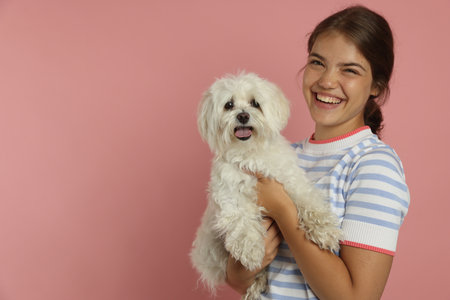 Happy teenage girl with dog on pink background, space for textの写真素材