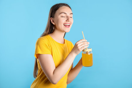 Woman with refreshing drink and straw on light blue backgroundの写真素材