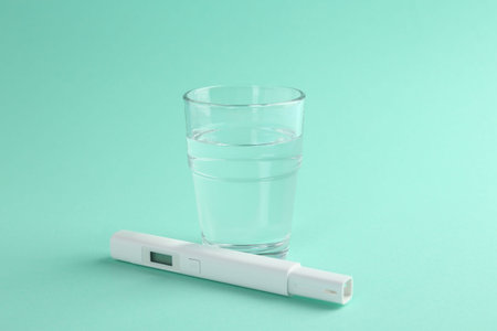 Nitrate tester and glass of water on turquoise background, closeupの写真素材