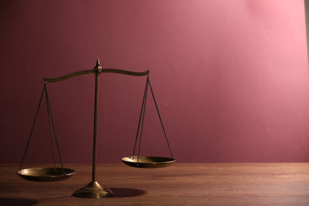 Scales of justice on wooden table against color background. Space for textの写真素材