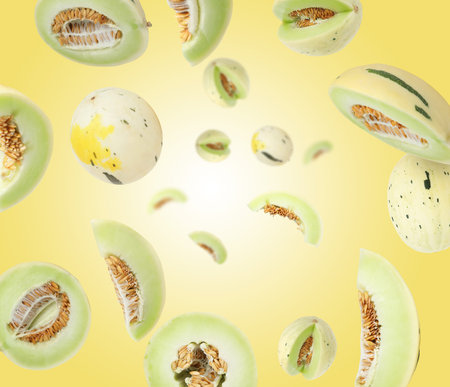 Tasty ripe melons swirling in air against yellow gradient backgroundの写真素材