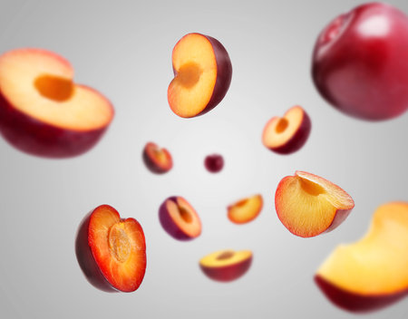 Fresh ripe plums swirling in air against gray backgroundの写真素材