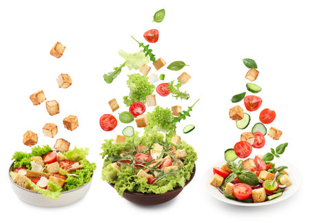 Croutons and other ingredients falling into bowls of salads against white background, setの写真素材