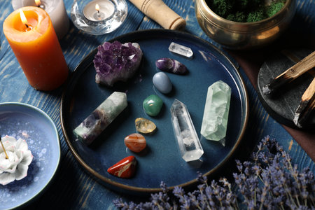 Chakra gemstones, lavender flowers, incense and burning candles on blue wooden table, closeupの写真素材