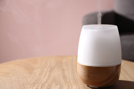 One stylish aroma lamp on wooden table against pink wall, closeup. Space for textの写真素材