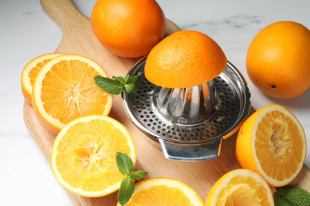 Squeezer with oranges and mint on white table, closeup. Making fresh juiceの写真素材