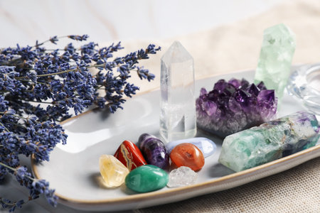 Different gemstones and lavender flowers on table, closeup