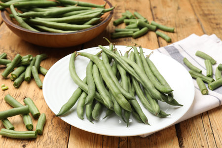 Many raw green beans on wooden table, closeup
