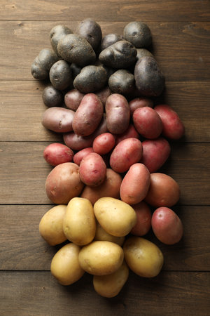 Different types of potatoes on wooden table, flat layの写真素材