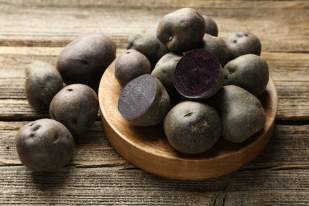 Fresh purple potatoes on wooden table, closeupの写真素材