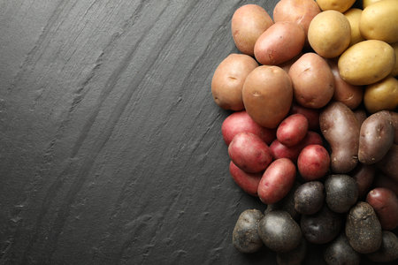 Different types of potatoes on black table, flat lay. Space for textの写真素材