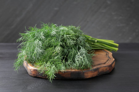 Bunch of fresh dill on black wooden table, closeup