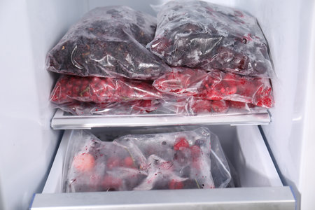 Different frozen berries in plastic bags in open fridgeの写真素材