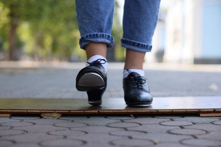 Teenage girl in tap shoes dancing outdoors, closeupの写真素材