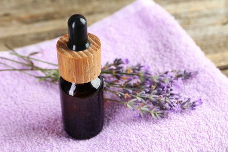 Lavender essential oil, flowers and towel on wooden table, closeupの写真素材