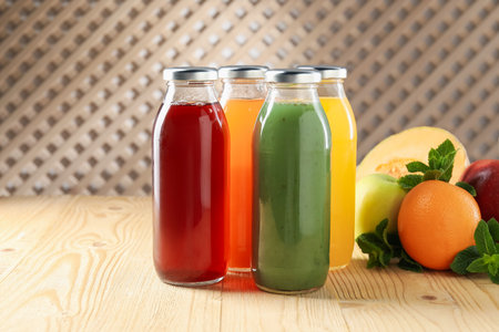 Tasty juices in glass bottles, fresh ingredients and mint on wooden table indoors, closeupの写真素材