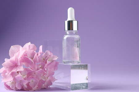Promotion. Bottle of cosmetic product, glass podium and hydrangea flowers on violet background, closeupの写真素材