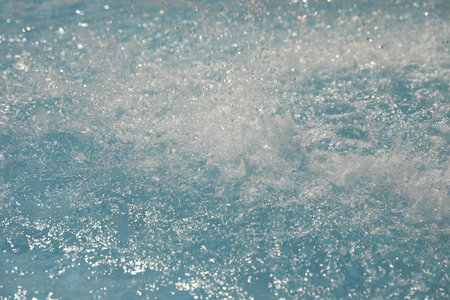 Splashes in swimming pool on sunny day. Summer vacation