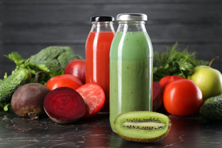 Tasty juices in glass bottles and ingredients on black marble table, closeupの写真素材