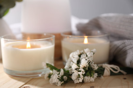 Burning candles and flowers on wooden table, closeupの写真素材