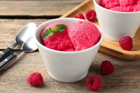 Delicious raspberry sorbet with mint in bowl and fresh berries on wooden table, closeupの写真素材