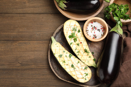 Halves of fresh eggplant, whole ones, spices and parsley on wooden table, flat lay. Space for textの写真素材