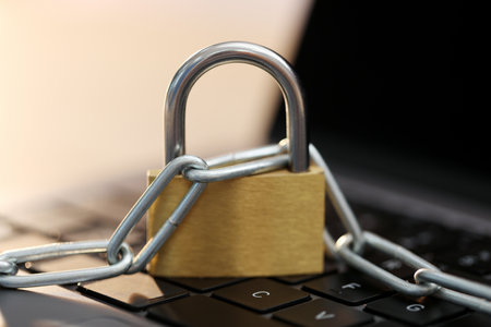 Cyber safety. Metal padlock with chain on laptop, closeupの写真素材