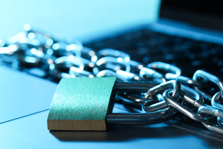 Cyber safety. Metal padlock with chain on laptop in color light, closeup