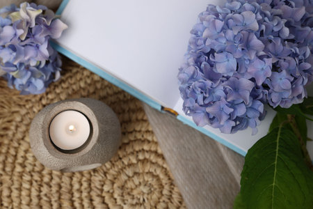 Spa composition with burning candle, book and beautiful hydrangea flowers on table, flat layの写真素材