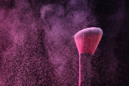 Makeup brush with pink eye shadow on black background, closeup. Space for textの写真素材