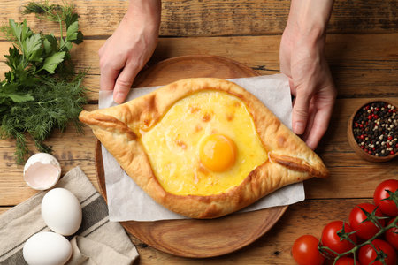 Woman with delicious khachapuri at wooden table, top viewの写真素材