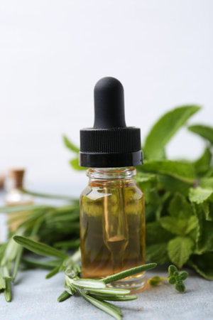 Bottle of essential oil and herbs on light grey table, closeupの写真素材