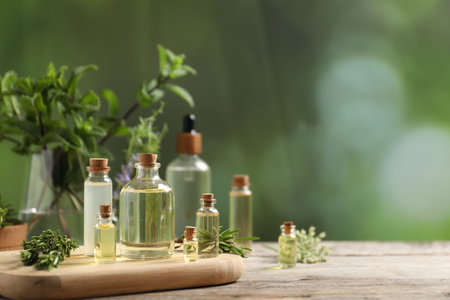 Bottles of essential oils and different herbs on wooden table outdoors, closeup. Space for textの写真素材