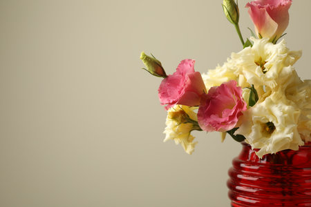 Beautiful flowers in glass vase on beige background, closeup. Space for textの写真素材