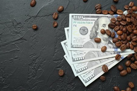 Dollar banknotes and roasted coffee beans on dark textured table, flat lay. Space for textの写真素材