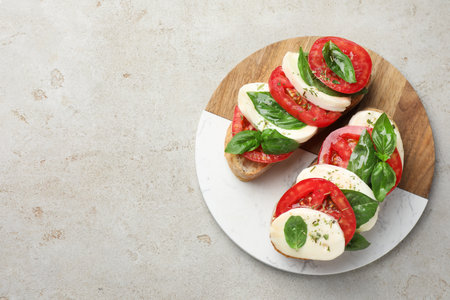 Sandwiches with mozzarella cheese, tomatoes and basil on light grey textured table, top view. Space for textの写真素材