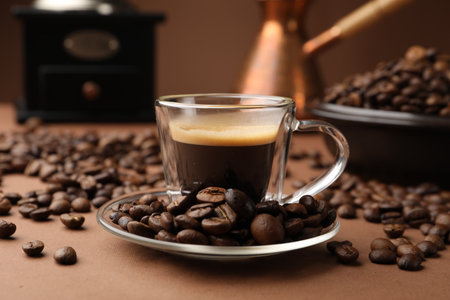 Cup of hot coffee, cezve, grinder and beans on brown background, closeupの写真素材
