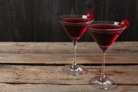 Martini cocktail with cherries in glasses on wooden table, closeup. Space for textの写真素材