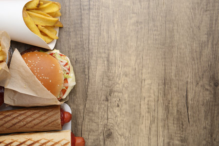 Different delicious fast food on wooden table, flat lay. Space for textの写真素材