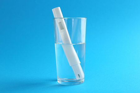 Nitrate tester in glass of water on light blue background