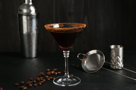 Martini cocktail with sugar in glass, coffee beans and shaker on black table, closeupの写真素材