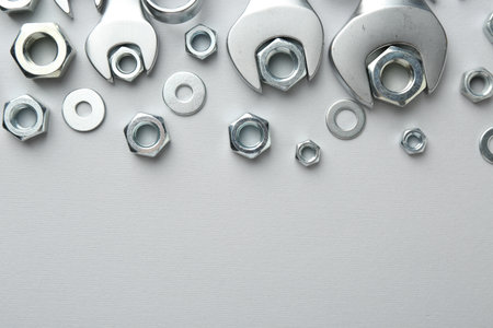 Metal wrenches and nuts on white background, flat lay. Space for textの写真素材