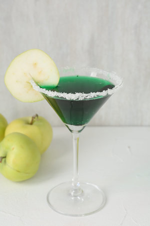 Martini cocktail with apple slice in glass and fruits on white table, closeupの写真素材