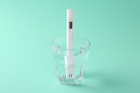 Nitrate tester in glass of water on turquoise background, closeup