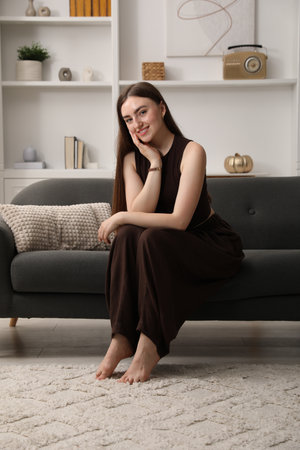 Beautiful woman sitting on sofa at homeの写真素材