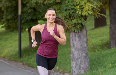 Athletic young woman in sportswear running outdoors, space for text