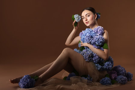 Beautiful young woman with hortensia flowers on brown backgroundの写真素材
