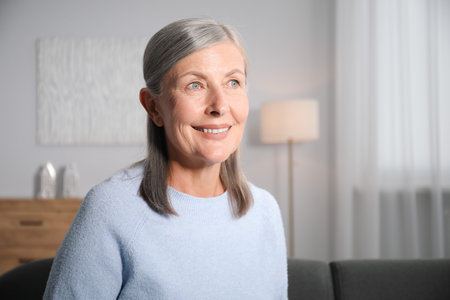 Elegant senior woman on sofa at home. Space for text