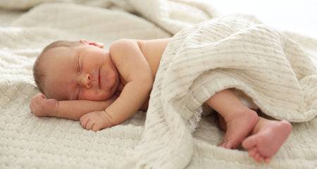 Cute newborn baby sleeping on bed indoors